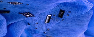 Arkaplan tasarımı dokusu, ipek desen, mavi kumaş ve dekoratif işlemeli taşlar.