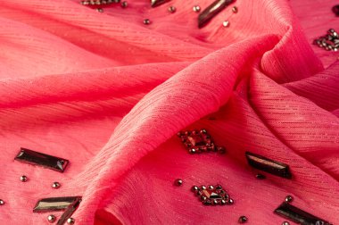 Arkaplan tasarımı dokusu, ipek desen, pembe kumaş ve dekoratif işlemeli taşlar.