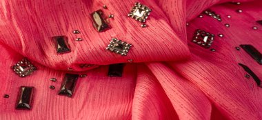 Arkaplan tasarımı dokusu, ipek desen, pembe kumaş ve dekoratif işlemeli taşlar.