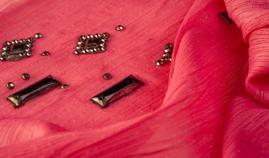 Arkaplan tasarımı dokusu, ipek desen, pembe kumaş ve dekoratif işlemeli taşlar.