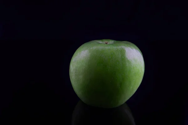 Green apple with reflection, on a black background, shallow depth of field. Concept, healthy food, lifestyle. — Stock Photo, Image