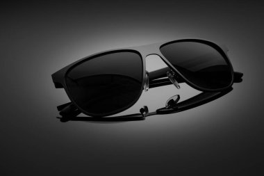 Sunglasses on a black gradient, matte background, shallow depth of field. The concept is stylish and beautiful.