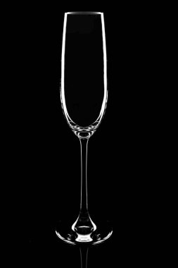 Empty champagne glass on a black background, elegantly illuminated on the sides. Concept, mysterious club life. Magazine and commercial photo with place for text or design, festival and holiday food