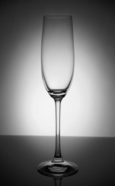 Empty champagne glass with reflection, on white and black gradient background. Concept, party and club life. Magazine and commercial photo with place for text or design, festival and holiday food and