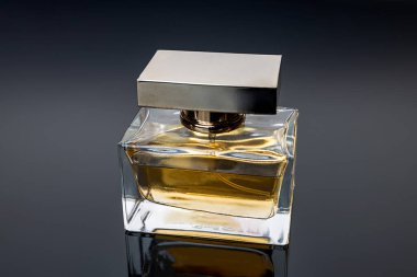 Perfume bottle in the rays of gray light on a black background. The play of light on a perfume bottle, can be used as a magazine and commercial photo with place for text or design