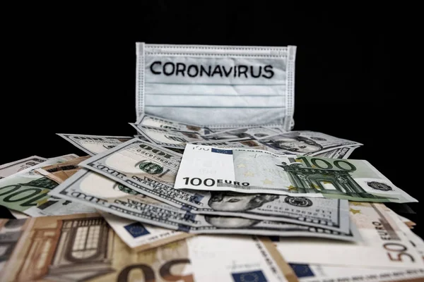 Inscrição de coroonavírus em uma máscara médica no topo das notas internacionais mundiais. Dólares americanos e euros. Aviso de Coronavirus . — Fotografia de Stock