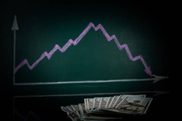 Money lies against the background of a stock drop chart .. The concept of profit decline, limited budget, loss-making business, capital outflow, report and financial crisis, low income and salary