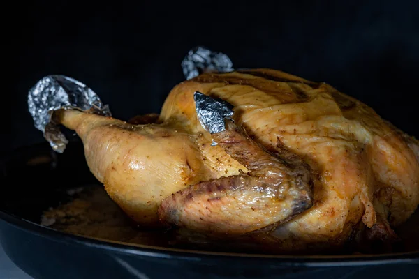 El pollo recién frito del horno casero, sobre el fondo negro, el primer plano, la profundidad superficial del campo. Concepto, cocina casera . — Foto de Stock