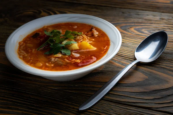 Kharcho soup with meat and rice on a wooden table, closeup, shallow depth of field. Concept, healthy food.
