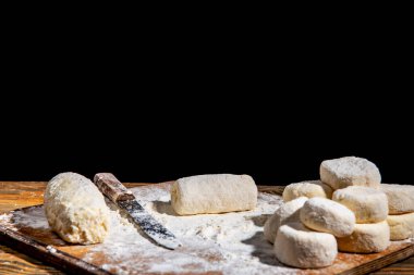 Dough prepared for baking on a wooden antique table on a dark background, close-up, shallow depth of field, beautiful directional lighting. The concept of home baking and comfort.