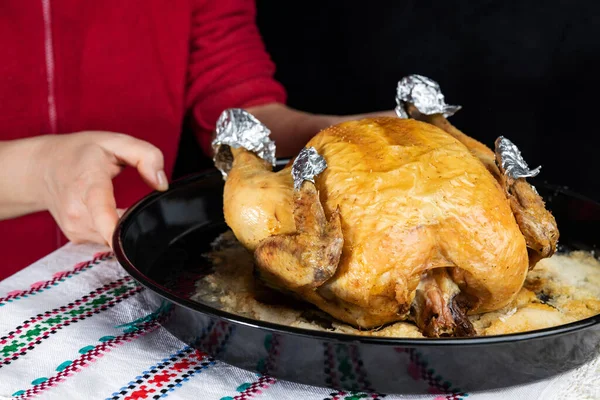 Las manos femeninas sirven pollo al horno sobre una mesa sobre un fondo oscuro, de cerca, de poca profundidad de campo. Concepto, comida sana casera . — Foto de Stock