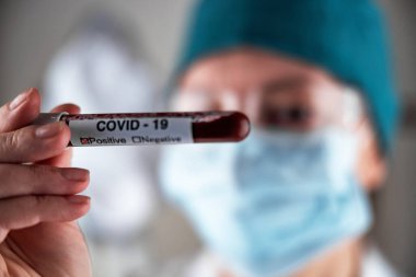 Yeni hızla yayılan koronavirüs için pozitif kan testi yapan solunum maskeli bir hemşire. Yakın plan, yüzeysel alan derinliği, seçici odaklanma. Covid 19 salgını kavramı