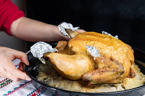 Las manos femeninas sirven pollo al horno sobre una mesa sobre un fondo oscuro, de cerca, de poca profundidad de campo. Concepto, comida sana casera . — Foto de Stock