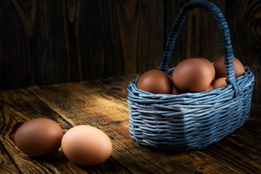 Paskalya yumurtaları tahtadan bir sepetin içinde koyu bir arka plan, sabah ışığı, yakın plan, sığ alan derinliği. Dini bayram kavramı, bahar havası..