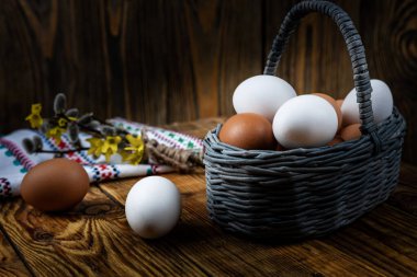Paskalya yumurtaları tahtadan bir sepetin içinde koyu bir arka plan, sabah ışığı, yakın plan, sığ alan derinliği. Dini bayram kavramı, bahar havası..
