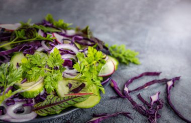 Açık gri bir masada sebzeli ve otlu salata, bulanık arka plan, açık arkaplan. Sağlıklı yeme kavramı.