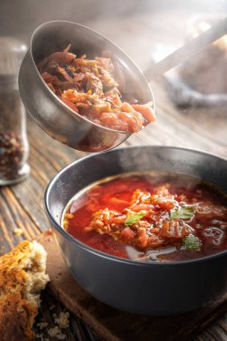 Borsch bir kepçeden bir kaseye dökülüyor, buhar, geleneksel bir Ukrayna sebze çorbası pancar, havuç, domates, patates, lahana, otlar ve sarımsak, yakın çekim derinliği,