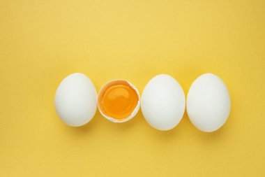Üst manzara, sarı arka planda izole edilmiş taze tavuk yumurtaları. Doğal sağlıklı gıda ve organik beslenme konsepti.