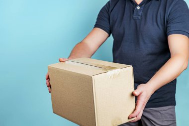 Açık gri arkaplan üzerinde paketleri olan kuryeyle teslimat hizmeti, sığ alan derinliği, seçici odak.