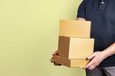 Açık gri arkaplan üzerinde paketleri olan kuryeyle teslimat hizmeti, sığ alan derinliği, seçici odak.