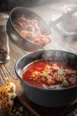 Borsch bir kepçeden bir kaseye dökülüyor, buhar, geleneksel bir Ukrayna sebze çorbası pancar, havuç, domates, patates, lahana, otlar ve sarımsak, yakın çekim derinliği,