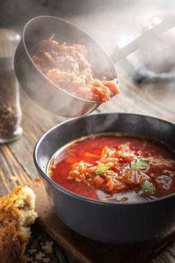 Borsch bir kepçeden bir kaseye dökülüyor, buhar, geleneksel bir Ukrayna sebze çorbası pancar, havuç, domates, patates, lahana, otlar ve sarımsak, yakın çekim derinliği,