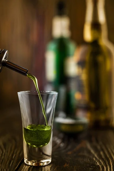 Ένα πράσινο αλκοολούχο ποτό χύνεται σε ένα ποτήρι σε ένα κλαμπ. Στο μπαρ. Προετοιμασία ενός πράσινου κοσμοπολίτικου cocktail, ρηχό βάθος πεδίου, επιλεκτική εστίαση. — Φωτογραφία Αρχείου