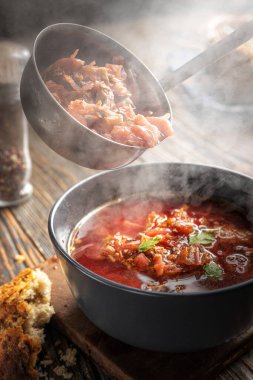 Borsch bir kepçeden bir kaseye dökülüyor, buhar, geleneksel bir Ukrayna sebze çorbası pancar, havuç, domates, patates, lahana, otlar ve sarımsak, yakın çekim derinliği,