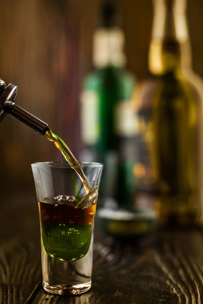 En grön alkoholhaltig dryck hälls i ett glas på en nattklubb. I baren. Förberedelse av en grön kosmopolitisk cocktail, grunt skärpedjup, selektivt fokus. — Stockfoto