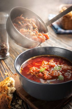 Borsch bir kepçeden bir kaseye dökülüyor, buhar, geleneksel bir Ukrayna sebze çorbası pancar, havuç, domates, patates, lahana, otlar ve sarımsak, yakın çekim derinliği,
