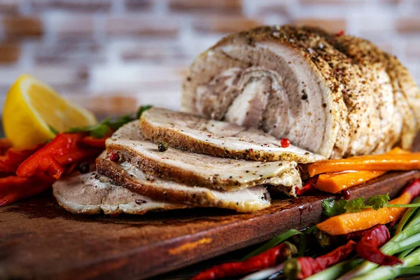 Cerdo horneado tradicional en rodajas adornado con hierbas, zanahorias de limón y especias, preparado para servir en la mesa festiva, primer plano, poca profundidad de campo, enfoque selectivo. El concepto de delicioso — Foto de Stock