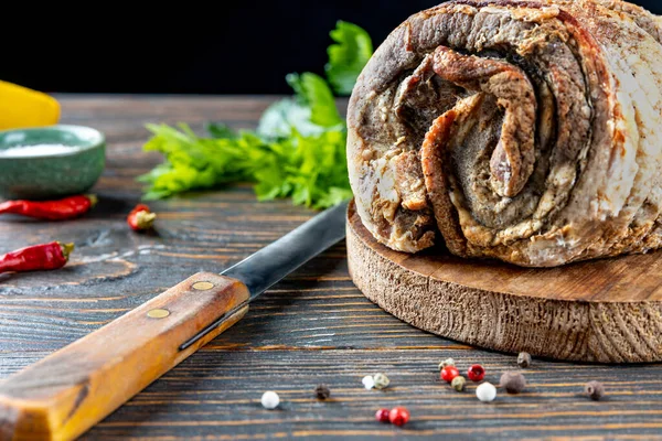 Leckeres gebratenes Schweinefleisch in Kräutern und Gewürzen in Nahaufnahme des ganzen Körpers auf einem Holzbrett gebacken, daneben ein Messer, Zitrone, Kräuter und Gewürze, geringe Schärfentiefe, selektiver Fokus. — Stockfoto