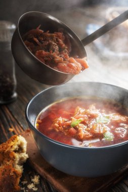 Sebzeli ve etli domates çorbası, buharın geldiği yerden bir kaseye dökülüyor, lezzetli, iştah açıcı geleneksel Ukrayna borsch 'u, yakın plan, sığ alan derinliği, seçici odaklanma.