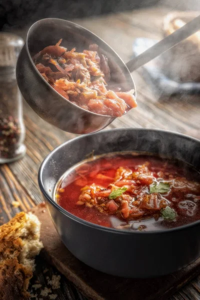 Sebzeli ve etli domates çorbası, buharın geldiği yerden bir kaseye dökülüyor, lezzetli, iştah açıcı geleneksel Ukrayna borsch 'u, yakın plan, sığ alan derinliği, seçici odaklanma.