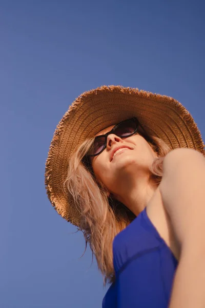 日の出にビーチで帽子とサングラスを被った若い女性の肖像画です — ストック写真