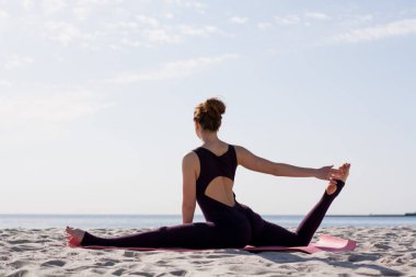 Yoga yapan kadın sabah güneşinde plajda antrenman yapıyor. 