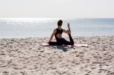 Yoga yapan kadın sabah güneşinde plajda antrenman yapıyor. 