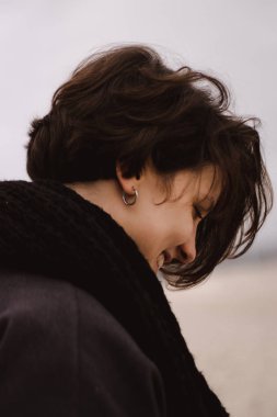 Genç ve güzel bir kadın deniz kenarında yürüyor, kışın açık havada.