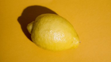 Sarı arka planda sulu bir dilim limon izole edilmiş.