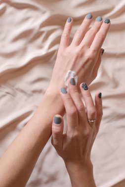 Kadın elleri cildine nemlendirici krem sürüyor.