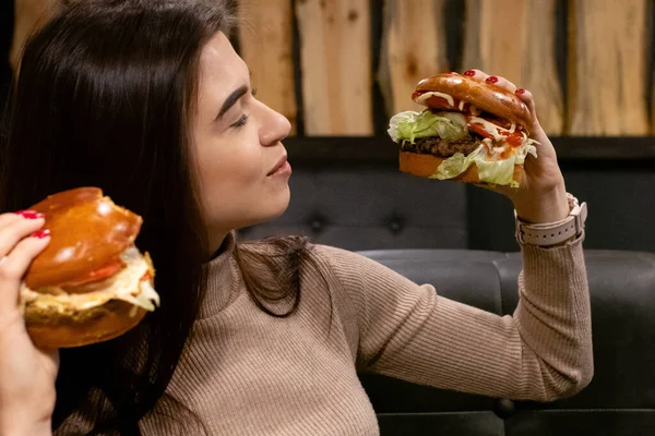 Hamburger yiyen, gülümseyen, aç genç bir kadının portresini yakından çek.