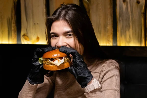 Hamburger yiyen, gülümseyen, aç genç bir kadının portresini yakından çek.