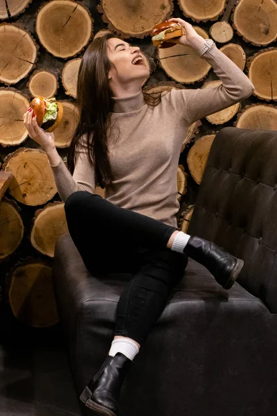 Hamburger yiyen, gülümseyen, aç genç bir kadının portresini yakından çek.