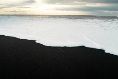 Kışın İzlanda 'daki kara kumsalda gün doğumu