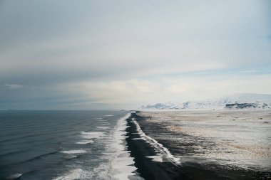 Kışın İzlanda 'daki kara kumsalda gün doğumu