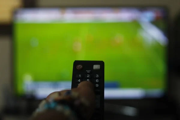 A person with a TV remote controls the remote control to switch channels to watch TV shows.