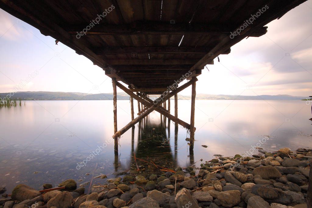 Old abandoned wooden fishing pier on the river in the countryside