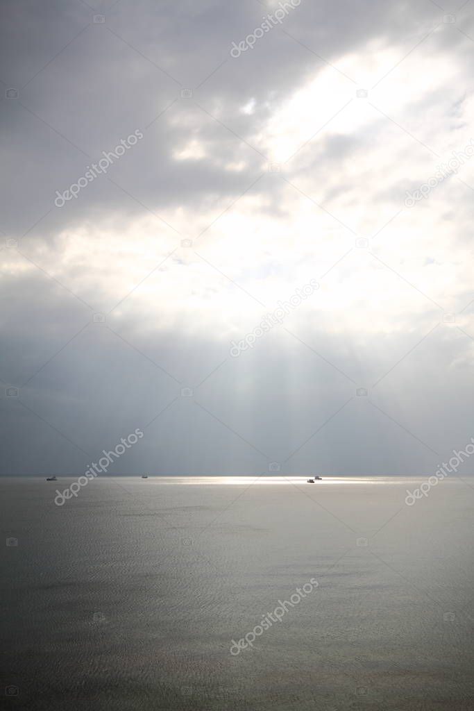 Sun rays beaming through picturesque clouds above the sea. Sun, clouds and water, sea photography.