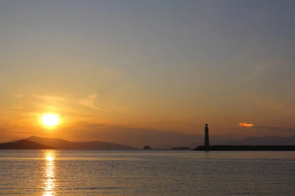 Seascape at sunset. Lighthouse on the coast. Seaside town of Turgutreis and spectacular sunsets