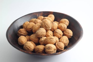 Beyaz arka planda izole edilmiş cevizler. Beyaz arka planda izole edilmiş ceviz yığını. Beyaz arka planda ahşap bir kasede ceviz. Metin için kopyalama alanı olan cevizler.